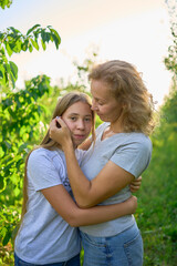 Wall Mural - mother and teenage girls with long blond hair spend time together in the sunlit park