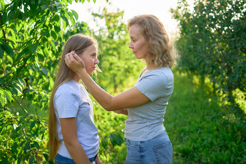 Wall Mural - mother and teenage girls with long blond hair spend time together in the sunlit park