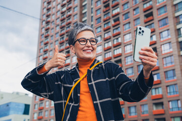 Canvas Print - Photo of pretty aged lady smart phone make selfie show thumb up walk fresh air street outdoors