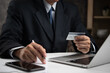 © khunkornStudio - Businessman using a credit card to make an online payment, symbolizing secure digital transactions. Great for e-commerce, fintech services, or online banking