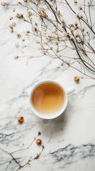 Cup of herbal tea surrounded by dried flowers on marble