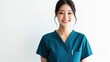 © Surachetsh - A young Asian nurse radiates positivity in teal scrubs, smiling with her hand in her pocket while looking at the camera against a white background.