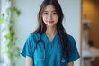 © Surachetsh - A young Asian nurse radiates positivity in teal scrubs, smiling with her hand in her pocket while looking at the camera against a white background.