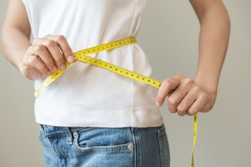 Wall Mural - Diet, slim shape asian young woman standing, hand using measure tape around waist, body. Happy, pleasure girl slim slender on white background. Diet session for wellbeing health, eat good food people.