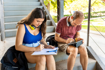 Couple of university students studying on the stairs of the faculty