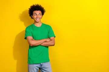 Photo of handsome good mood guy wear green t-shirt smiling arms folded emtpy space isolated yellow color background