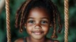 © Dulemegapixel - A close-up of a smiling young girl with dreadlocks, exuberant and happy while seated on a playground swing, epitomizing carefree childhood joy amidst greenery.