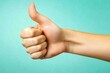 © Viam - Close-up of thumbs-up gesture on teal background