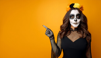 Wall Mural - happy halloween concept terrified woman special outfit white clay skull makeup black clothes pointing towards blank space yellow background