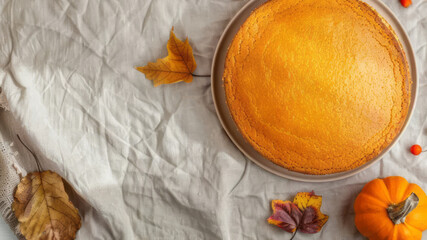 Fall homemade pumpkin cake, wheat on rustic linen textile background with copy space. Classic Thanksgiving pastry tart. Top view, flat lay. Autumn concept for banner, poster, flyer, greeting card