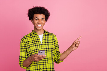 Sticker - Portrait of nice young man smart phone point finger empty space wear shirt isolated on pink color background