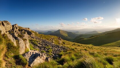 Wall Mural - a sunny rocky hillside features a grassy foreground and distant hills as its backdrop