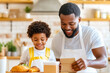 © zamuruev - A father and his child joyfully prepare baked goods together, sharing smiles and quality time in a bright and cheerful kitchen