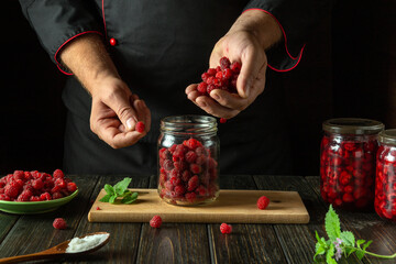 Sticker - The cook fills the jar with raspberries. The process of making a sweet drink from fresh berries and sugar on the kitchen table. Preserving raspberry in a jar