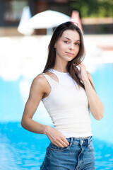 Wall Mural -  woman in jeans and white shirt sitting near the summer pool