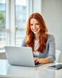 © AniMei - Smiling young woman sitting with a laptop at the table.