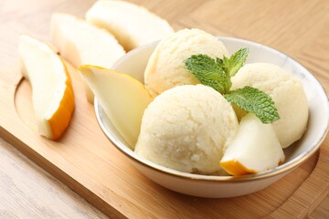 Wall Mural - Scoops of tasty melon sorbet with mint in bowl and fresh fruit on wooden table, closeup