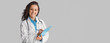 © Prostock-studio - Portrait of smiling young woman doctor in uniform holding clipboard, looking and smiling at camera, friendly therapist woman with stethoscope posing on grey wall background, copy space