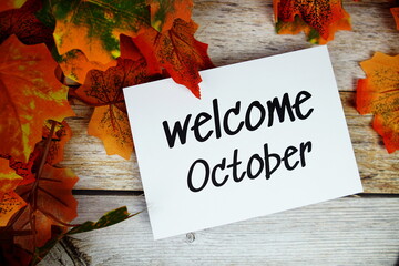 Sticker - Welcome October text with maple leaf decoration top view on wooden background