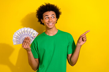 Poster - Photo of handsome good mood guy wear green t-shirt rising cash fan showing emtpy space isolated yellow color background