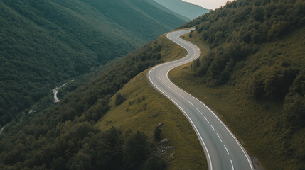 Aerial view of a serpentine asphalt road winding through rugged mountains, highlighting the dramatic landscape and open road for extra design elements or information. photo