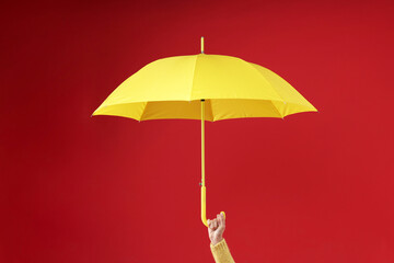 Wall Mural - Woman with yellow umbrella on red background, closeup