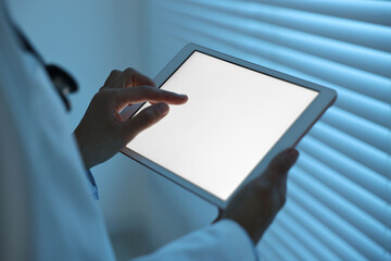 Wall Mural - Doctor using tablet in hospital at night, closeup