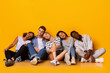 © Prostock-studio - Tired multiracial classmates sitting on floor and sleeping after exams over yellow background