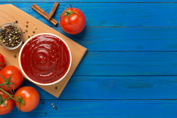 Delicious ketchup with spices and tomatoes on wooden background, top view