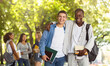 © Prostock-studio - Two international students smiling guys posing at camera at public park, having break while studying