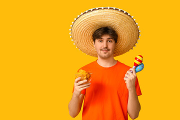 Sticker - Portrait of young man with sombrero, maracas and tortilla chips on yellow background. National Tortilla Chip Day celebration