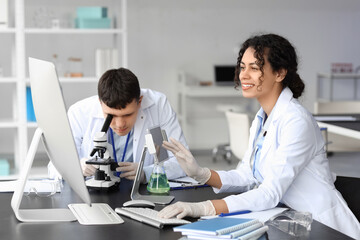 Wall Mural - Young chemists working at table in laboratory