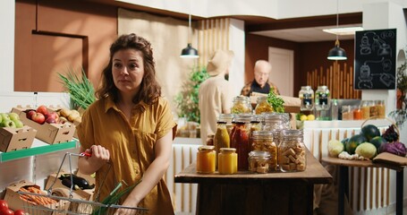 Canvas Print - Vegan woman buying organic pantry staples from zero waste supermarket. Smiling client shopping for bulk food products in biodegradable glass jars from local neighborhood store