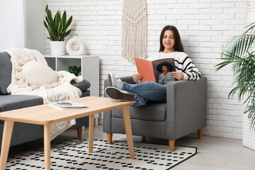 Sticker - Young woman reading magazine on armchair in living room