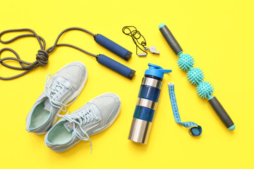 Wall Mural - Sneakers, measuring tape and different sports equipment on yellow background