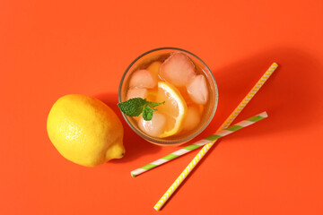 Wall Mural - Glass of tasty cold ice tea, paper straws and lemon on red background