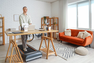 Sticker - Young man working with laptop on treadmill at table in office