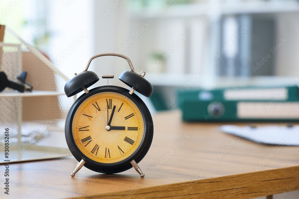 Black alarm clock on desk in office, closeup