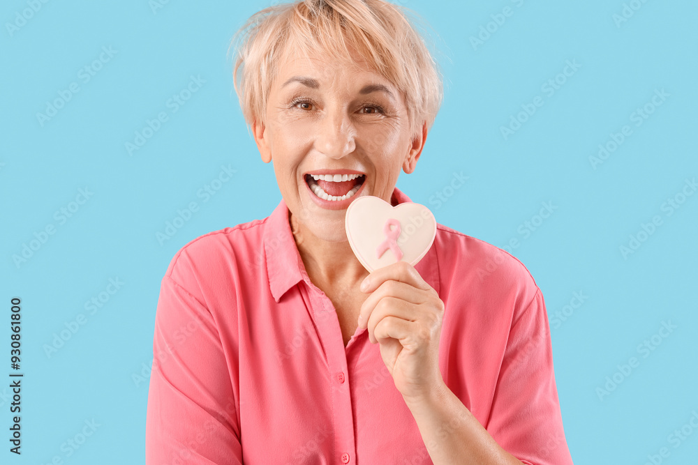 Mature woman with cookie on blue background. Breast cancer awareness concept