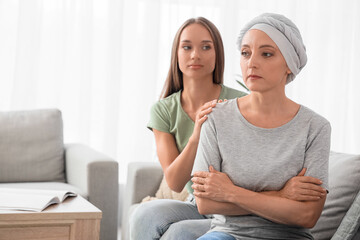 Canvas Print - Sad mature woman after chemotherapy with her daughter sitting on sofa at home