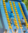 © JackF - Two male friends having fun in outdoor amusement park on summer day, climbing on inflatable slide with wooden poles..