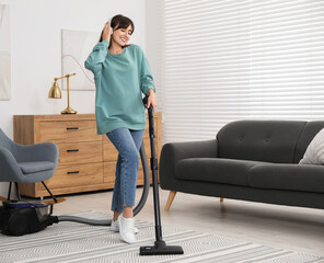 Wall Mural - Young woman in headphones vacuuming carpet at home