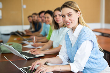 Sticker - Woman studying with group of students in university, using laptop.