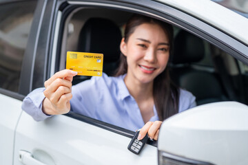 Wall Mural - Portrait of Asian woman driver holding credit card while sitting in car. 