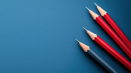 Four sharpened pencils, three red and one blue, placed on a blue background, representing creativity, education, and writing.