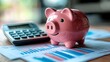 © keks20034 - A pink piggy bank on the background of financial charts and a calculator symbolizes financial management