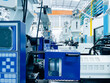 © TongTa - High-tech plastic injection molding machines lined up in a modern factory.