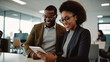 © halo - A Black woman and man in an office, looking at the tablet screen together with smiles on their faces.
