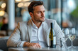 © Юлия Падина - Young man sitting in an upscale restaurant with a bottle of wine, looking thoughtful and stylishly dressed, creating a sophisticated dining atmosphere