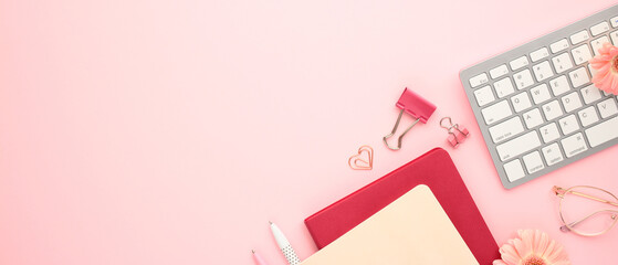 Wall Mural - Aesthetics minimal workspace with paper notebooks, keyboard, eyeglasses, clips on pastel pink background. Flat lay, top view